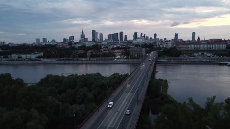 Filmische-Drohnenaufnahmen-Der-Warschauer-Skyline-Mit-Weichsel-Und-Brücke-Voller-Verkehr-Am-Abend