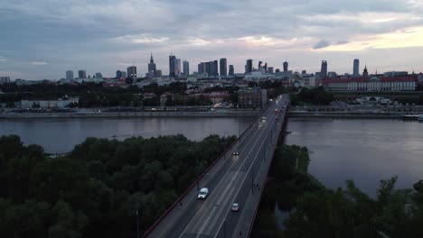 cinematic drone footage of warsaw skyline with vistula river and bridge filled with traffic in the evening