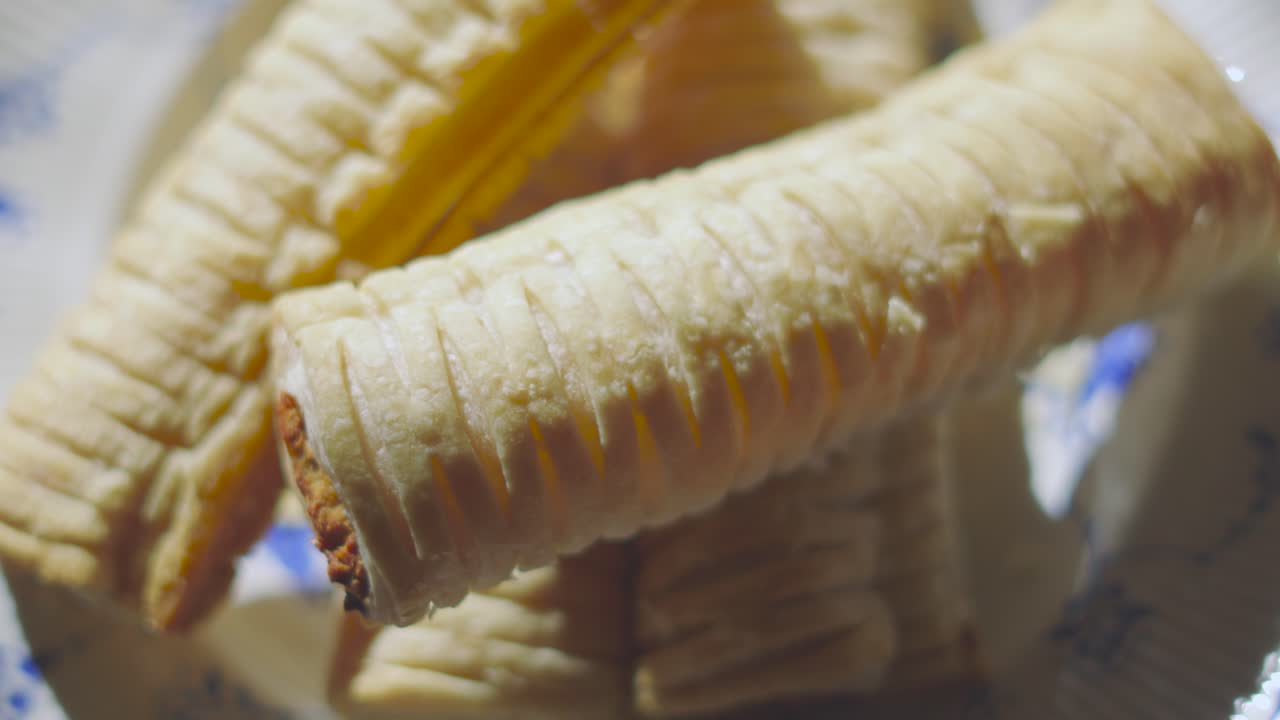 Top Down Rotating View of Sausage Rolls on Plate After Baking in Bright Natural Sunlight. Delicious Traditional English Fresh Bakery Product. British Snack Cuisine. Pork Meat Wrapped in Puff Pastry.