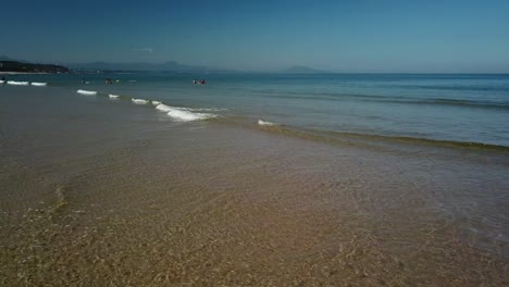 Shoreline-of-Biarritz-beach-with-people-bathing-in-background-on-sunny-day,-France