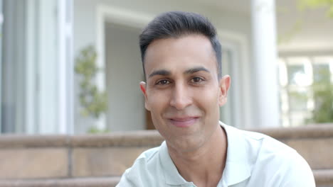 Portrait-of-happy-biracial-man-smiling,-sitting-in-sunny-garden,-copy-space,-slow-motion