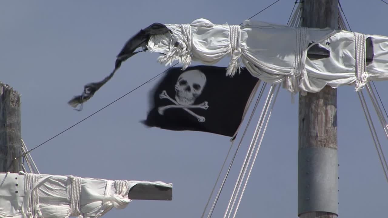 bandera pirata ondeando en el viento, en el mástil de un velero