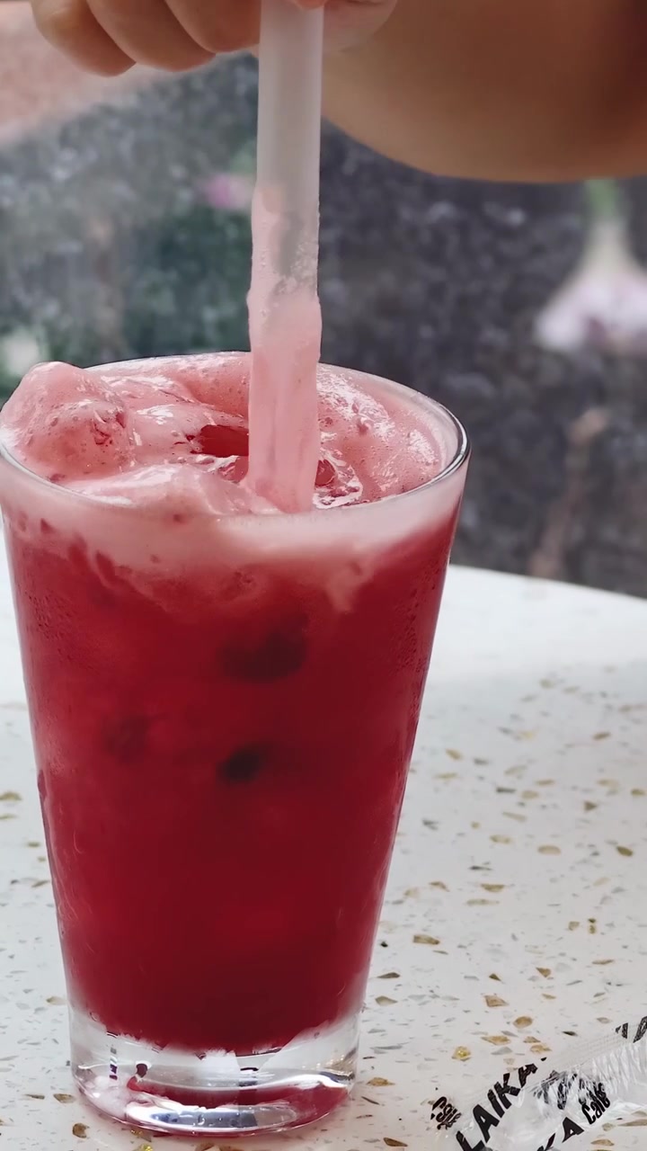 Mano che mescola una bevanda rossa con una cannuccia