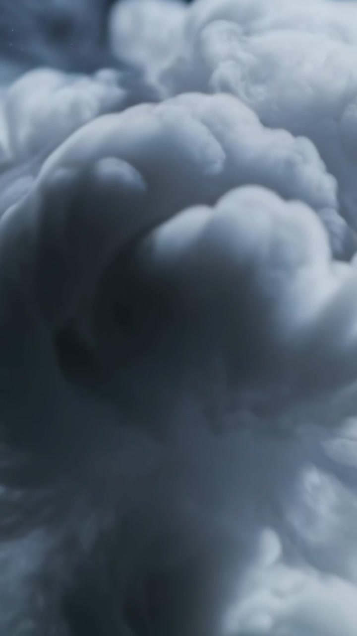 Video verticale: Un pennacchio grigio entra dall'alto, scende a cascata in un serbatoio seguendo il flusso contro uno sfondo scuro.