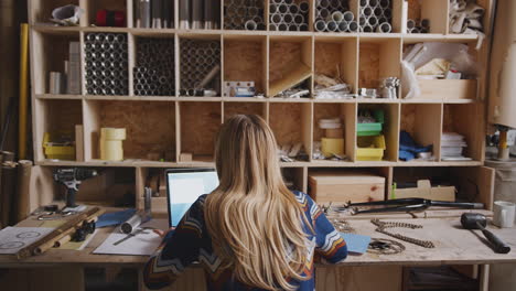 rear view of female designer in workshop working late on components for hand built bicycle