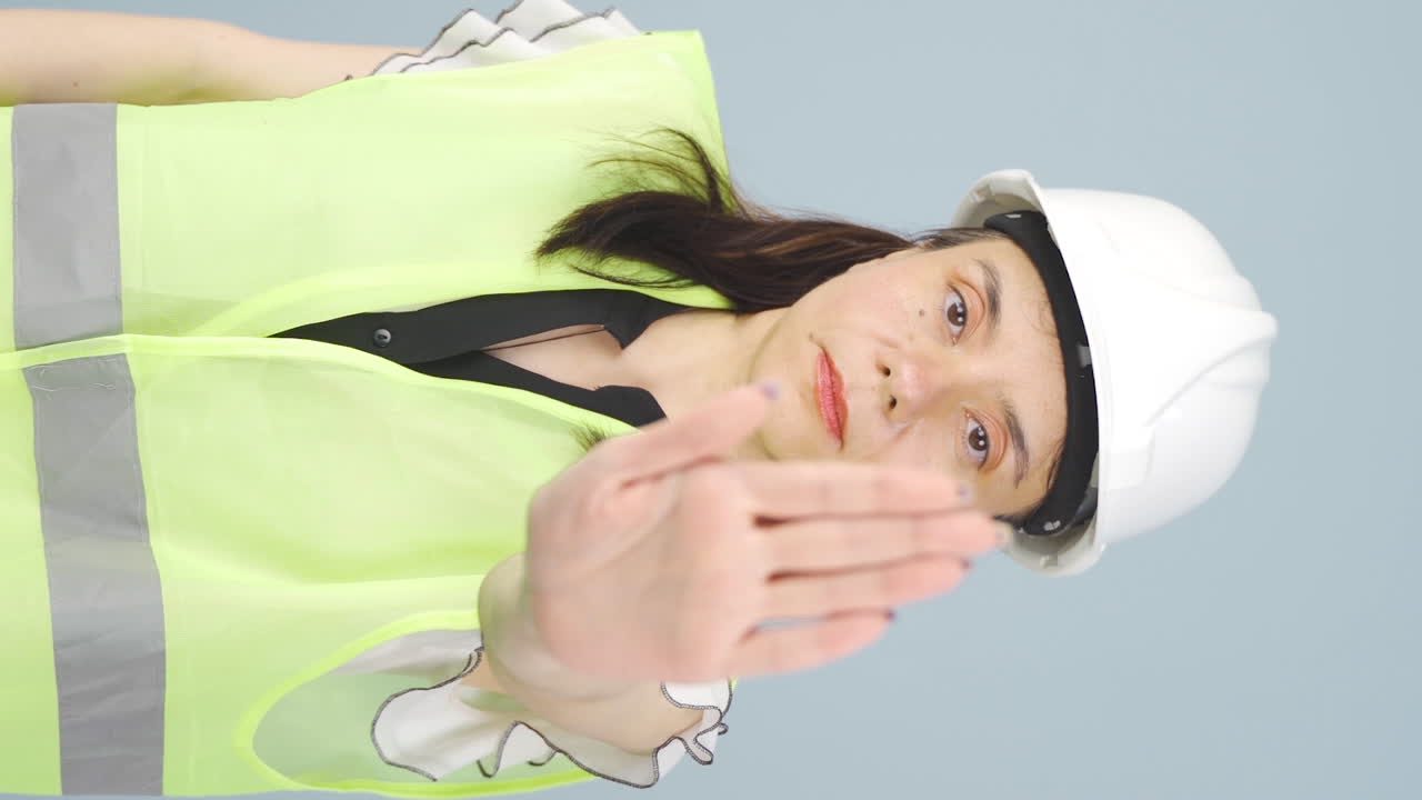 vídeo vertical del ingeniero mira a la cámara y hace una señal de alto.