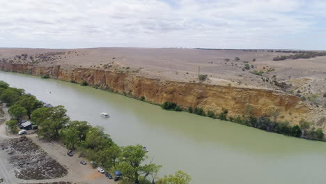 aerial shot moving across the stunning river murray and limestone cliffs as boats cruise down the river in south australia