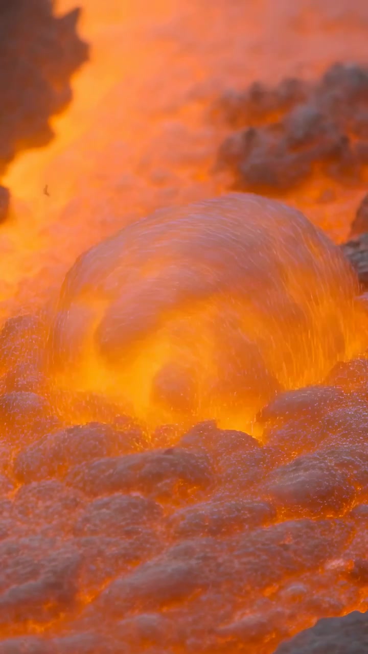 Video verticale: Flusso di materiale fuso che scorre, formando cupole e croste in un canale roccioso, spinto dal calore.