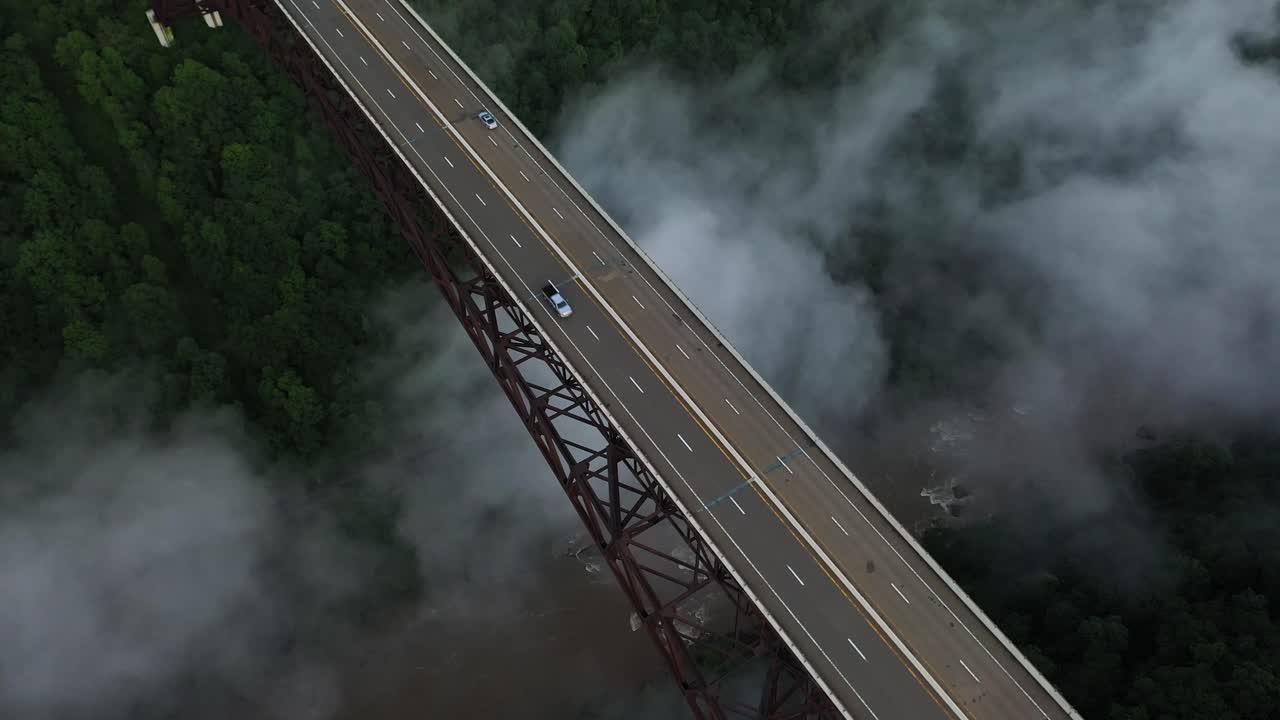Cinematic Aerial View of Cars Moving on Bridge Above Deep Canyon and Fog of New River Gorge, West Virginia USA