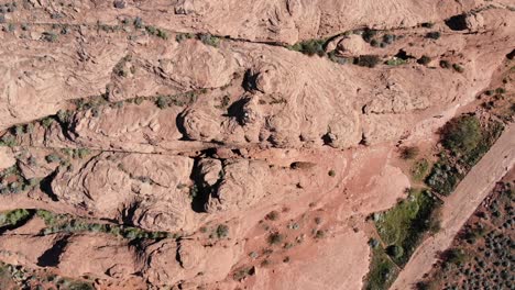 Drone-looking-down-on-red-rock-desert-while-rising-vertically