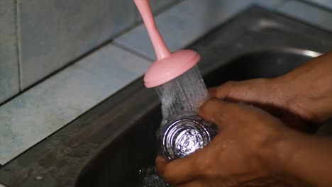 asian hands are washing drinking glasses using a foam sponge