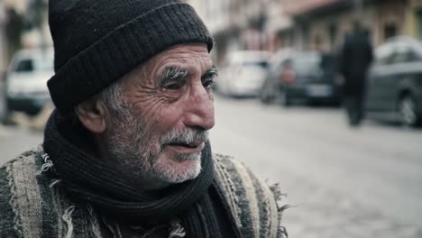 a charming elderly man wearing a knitted hat and a scarf sits on a bustling street. he gazes thoughtfully at passersby, surrounded by the vibrant atmosphere of the town.