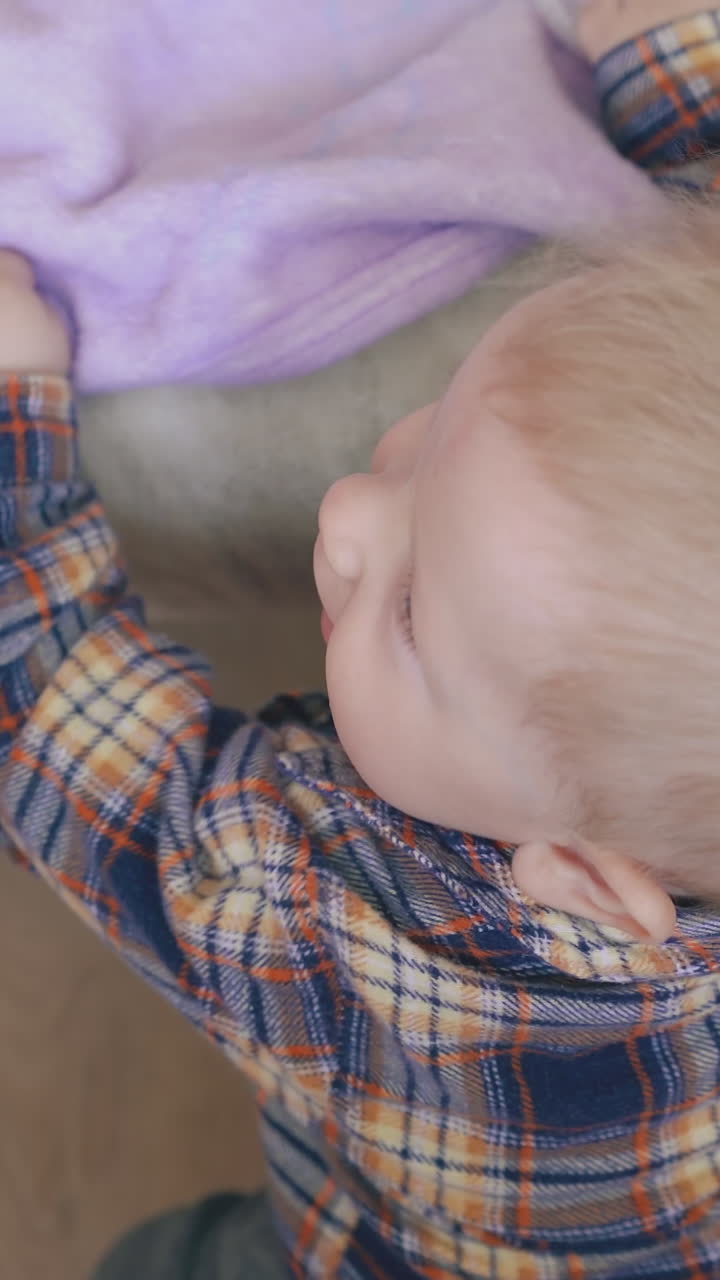 active little boy in shirt with aspirator climbs up on large soft bed in light children room close upper view