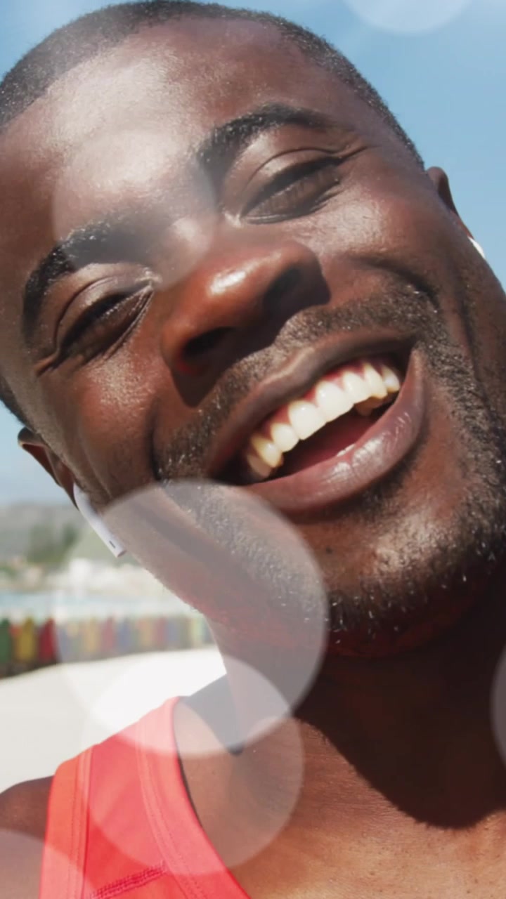 Animazione di luci brillanti su un uomo afroamericano felice che si allena, mentre fa una videochiamata e saluta.