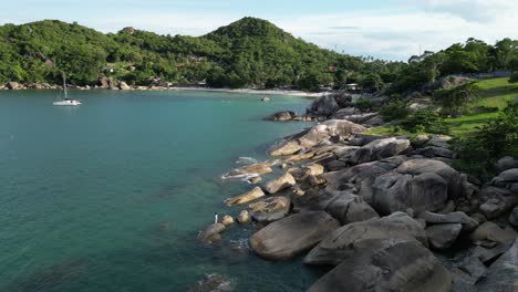 Statische-Aufnahme-Eines-Felsigen-Strandes-In-Den-Inselgruppen-Von-Koh-Samui-Mit-Stillem-Wasser-Und-Ufer-Und-In-Der-Nähe-Angedocktem-Boot