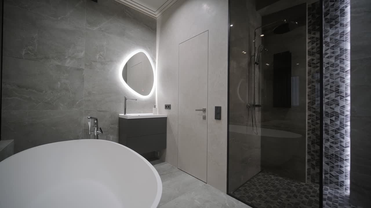 A spacious bathroom design featuring a sleek freestanding tub, illuminated mirror, and a walk-in shower with detailed tile work