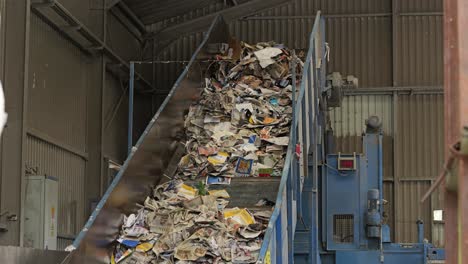 traktor, der papierabfälle zur belastung hinzufügt, bewegt sich auf dem förderband in einer papierrecyclinganlage nach oben