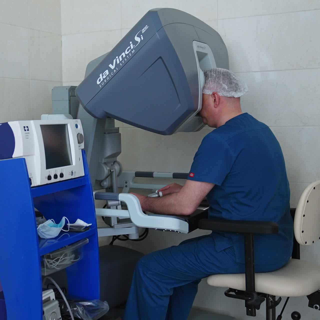 Male doctor controlling the high technological robotic equipment. Specialist rules Da Vinci surgical system and looks in binocular