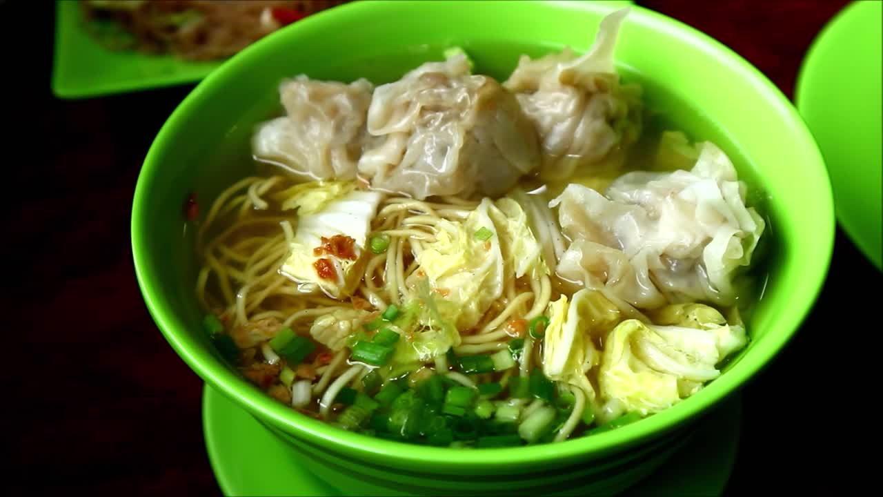 Close up handheld video shot of freshly cooked wanton noodle soup in a bowl