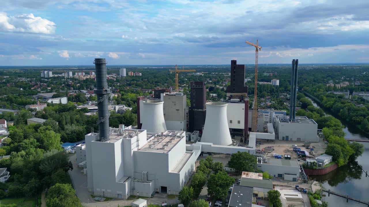 Power plant undergoing conversion, retrofitting and renewal, featuring cooling towers, chimneys, and construction crane. Best aerial view flight panorama orbit drone