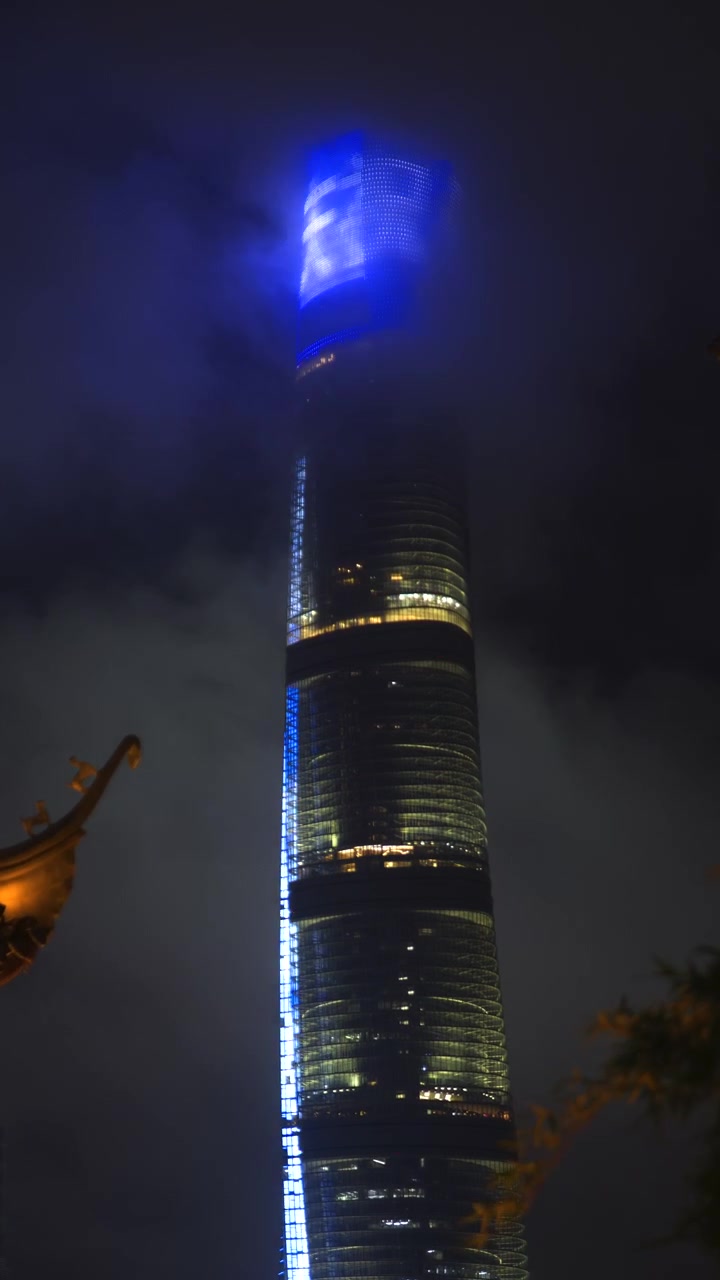 Torre di Shanghai illuminata di notte con nuvole in movimento