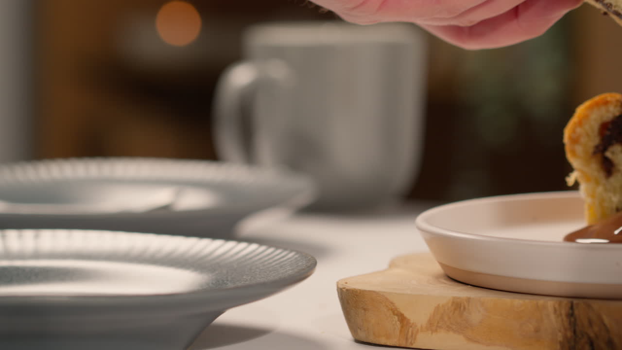 녹은 초콜릿 소스에 인 초콜릿 바바 을 집어 들고 접시에 넣는 사람의 근접 사진