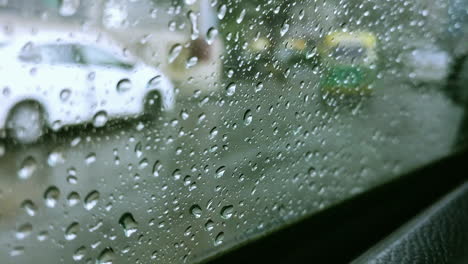 fast moving car in traffic with its window covered in water droplets focus during heavy rainfall