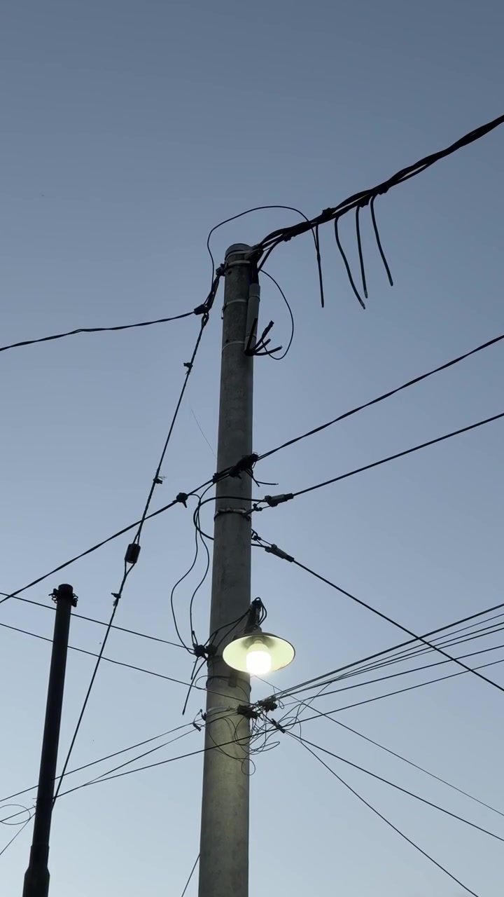 Illuminated Street Lamp on Utility Pole at Dusk
