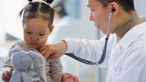 asian pediatrician examining little girl with stethoscope