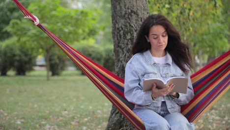 woman reading in a hammock in a park