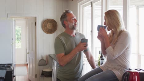 relajante pareja caucásica madura bebiendo café y hablando en la cocina