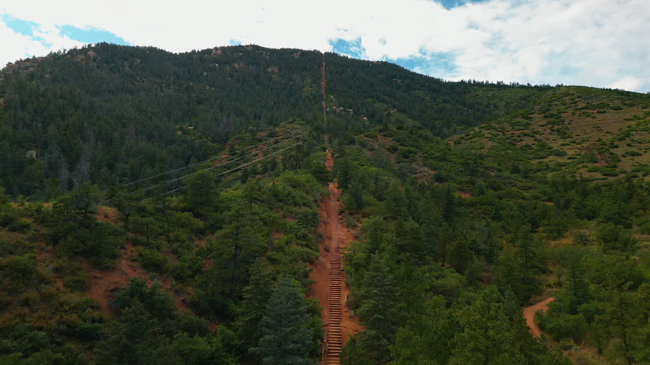 Flying above the steps leading to the top of the green mountain. Famous touristic attraction of the Manitou Springs Incline in Colorado, USA from drone