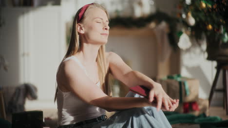 Mujer-Relajada-Con-Los-Ojos-Cerrados-Sosteniendo-Un-Libro-En-Una-Casa-Luminosa-Durante-La-Navidad