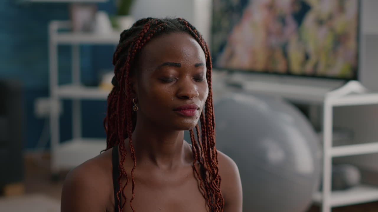 몸의 근육을  ⁇ 는 로터스 자세로 앉아 있는  ⁇ 은 피트 흑인 여성 트레이너의 초상화