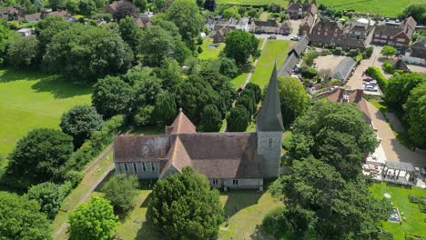 a downward aerial tilt of st john the evangelist church, tilting down to reveal the village of ickham in the background