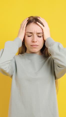young woman suffering from headache on yellow background