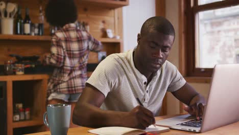 African-man-working-while-mixed-race-woman-preparing-breakfast