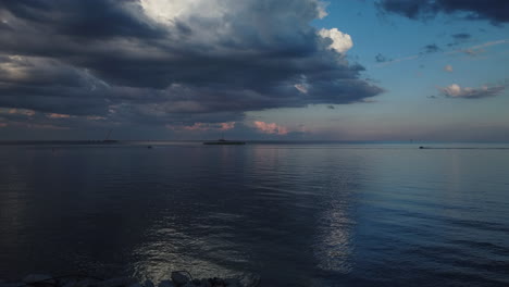 wide shot of sea doos skimming across a calm lake ontario towards a darkening sky