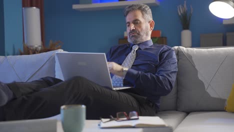 Thoughtful-businessman-relaxing-on-sofa-at-home-working-on-laptop,-thinking-creative-and-genius-ideas.