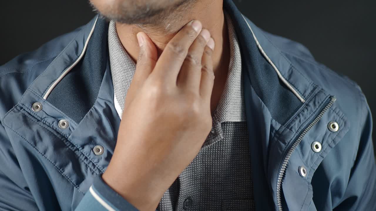 un hombre tocando su garganta con la mano