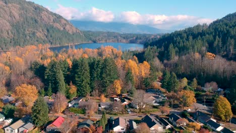 Drone-shot-of-small-town-with-lake-and-mountains-in-the-fall