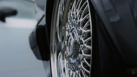 zooming in, the close-up reveals the wheel of the black car, exuding a sleek and polished appearance