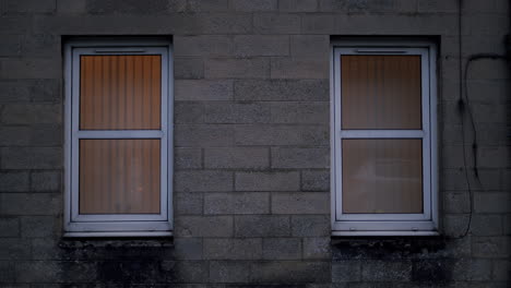 two plastic frame windows on cinder block building facade, handheld shot