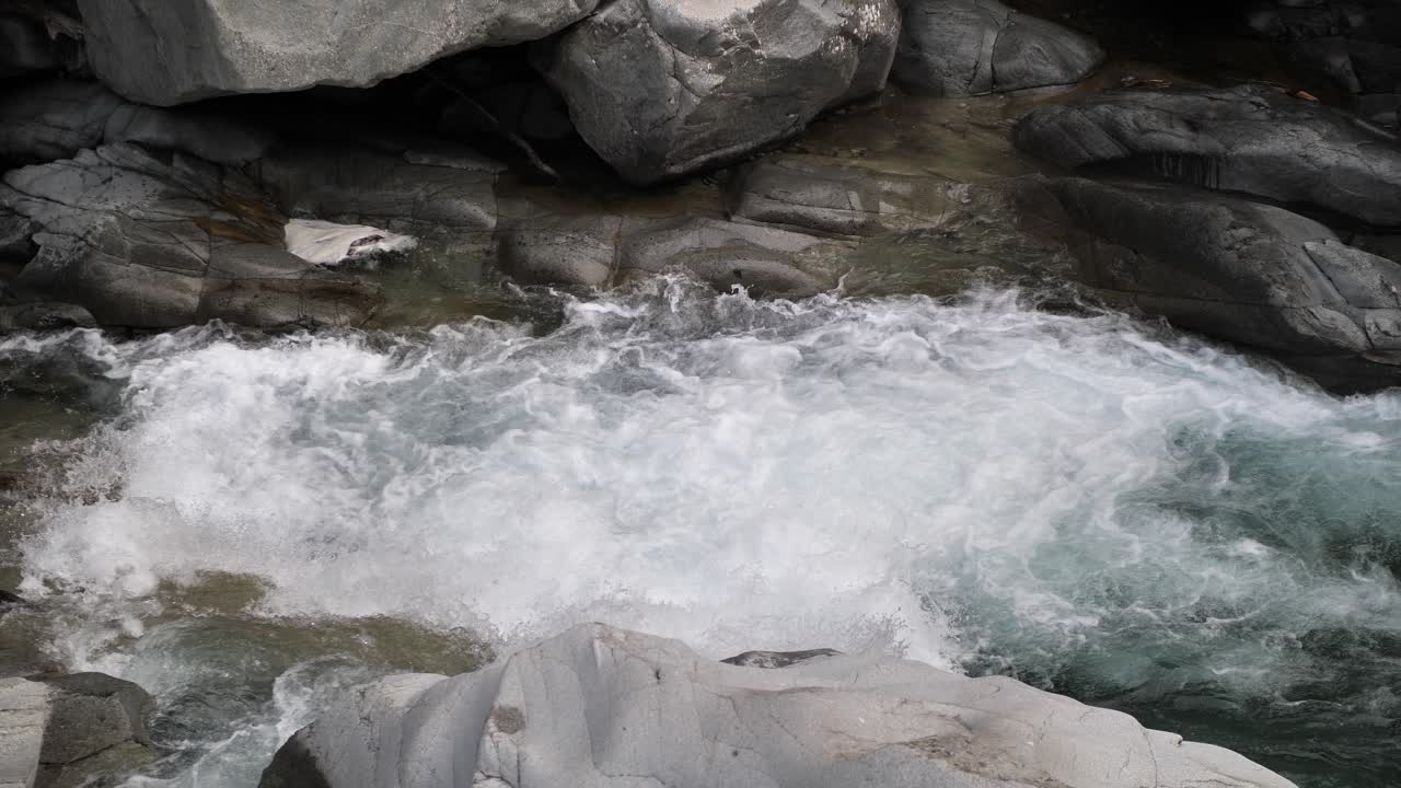 water streaming on high speed over a waterfall between the rocks in lauterbrunnen in Switzerland. Medium shot