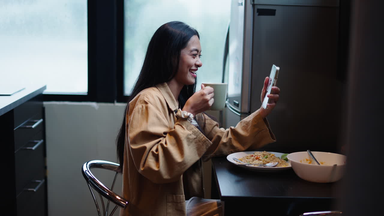 Woman enjoying a meal and using her phone in the kitchen