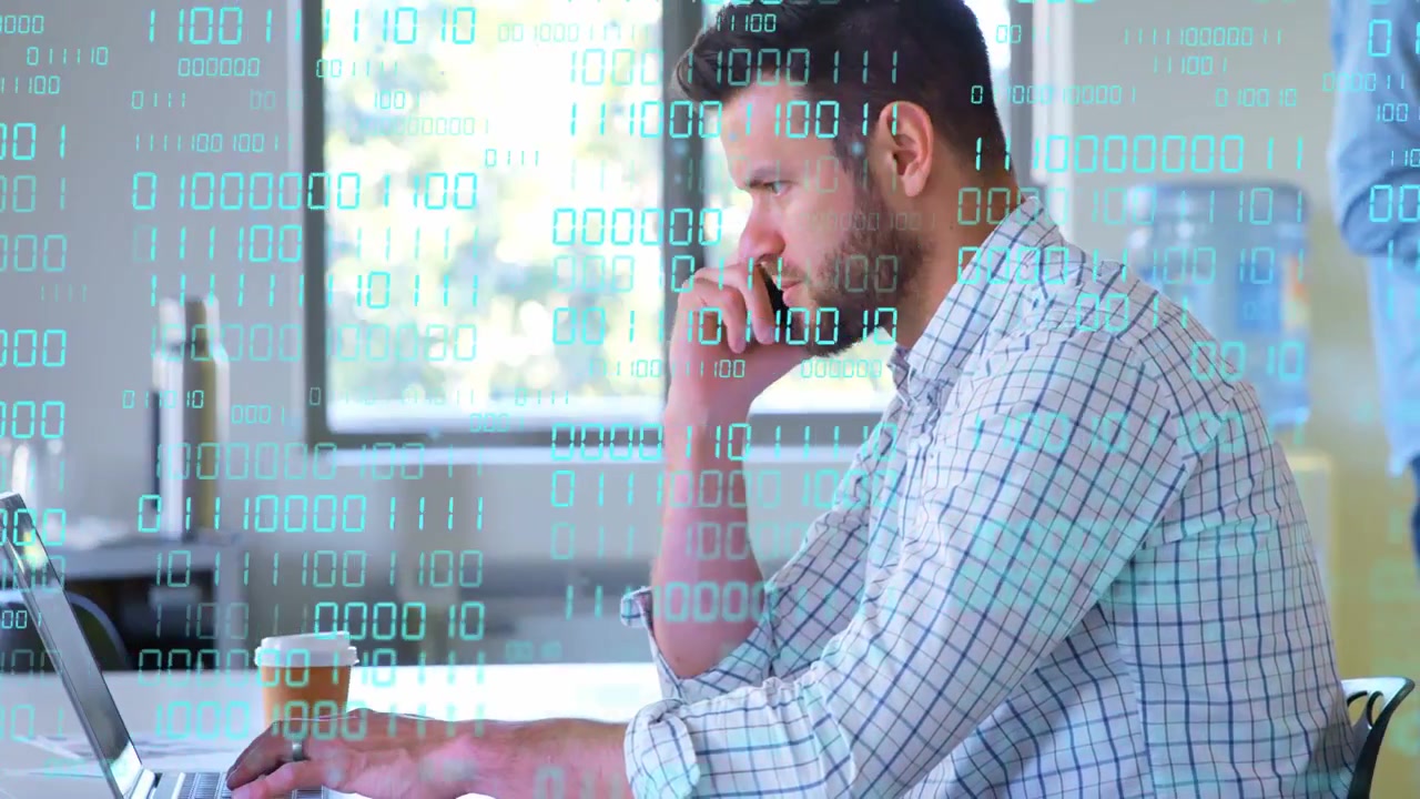 Man answering call while typing on laptop, binary overlay scrolling across display for tech work