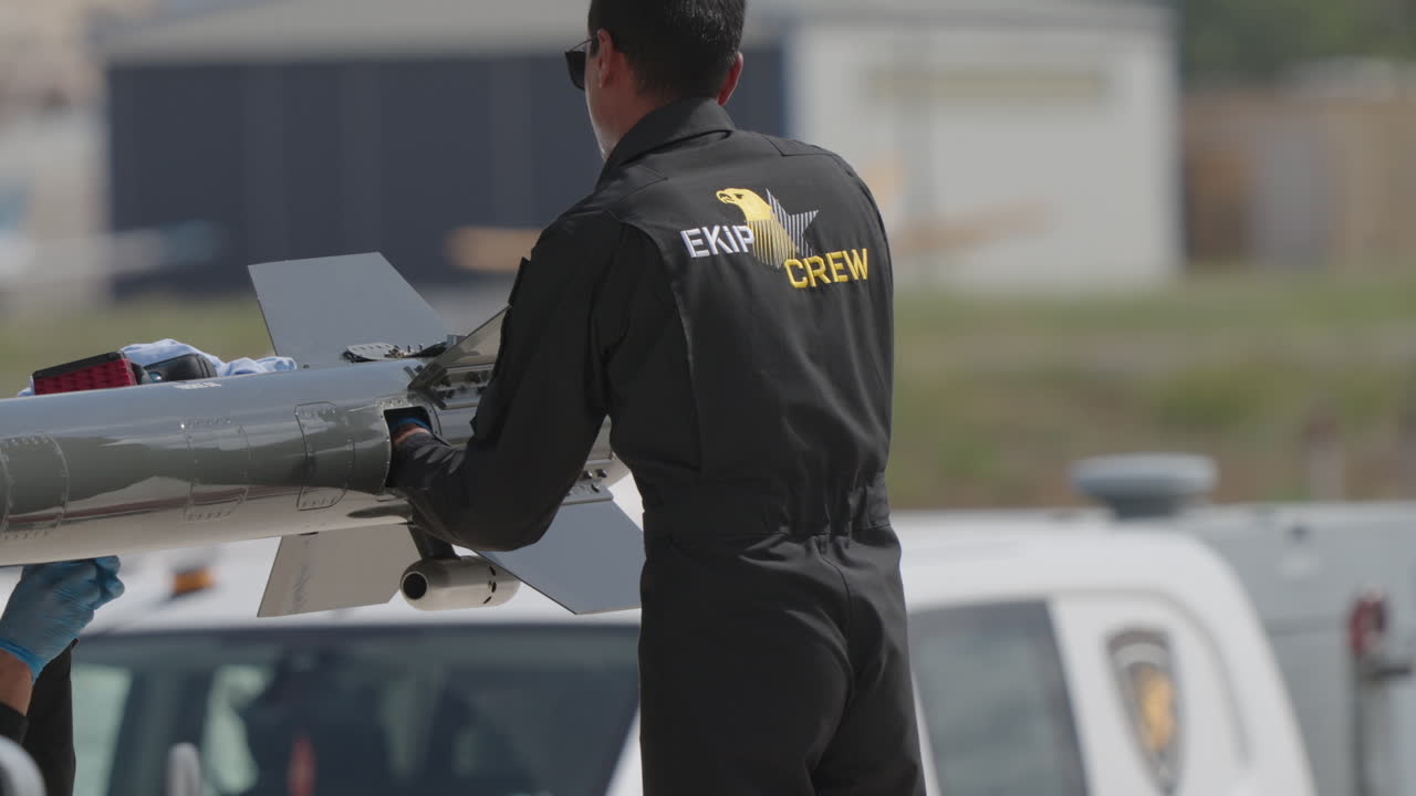 Crew Member Inspecting a Missile or Drone on an Airfield