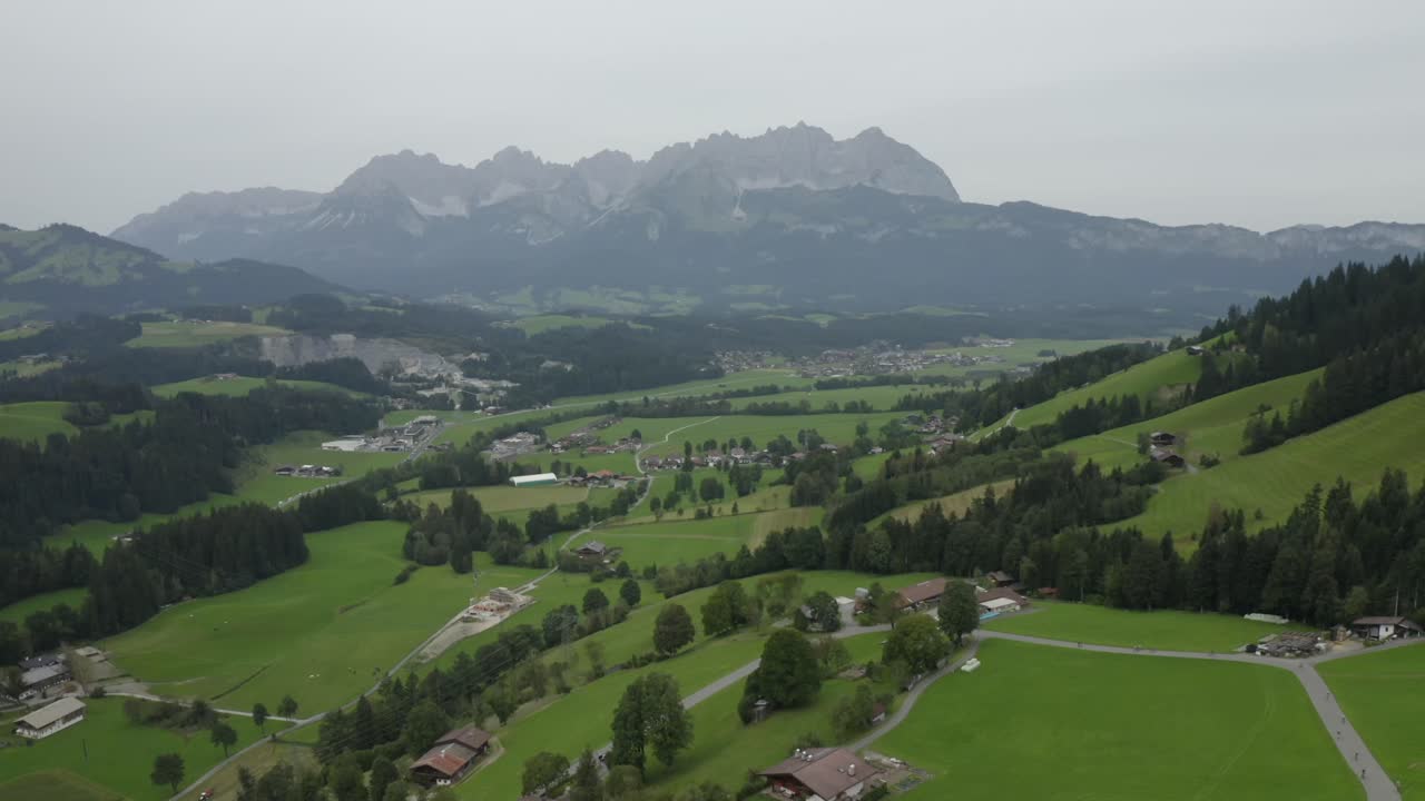 Wide-angle aerial view of a green alpine valley with a river flowing through quaint Austrian villages.