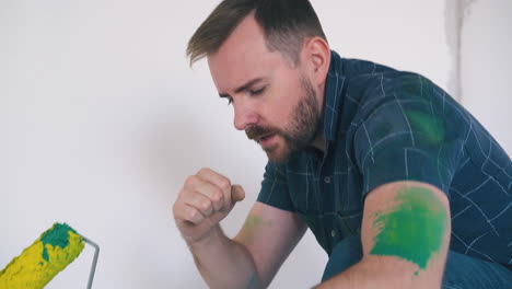 funny guy poses with roller at white wall in repairing room