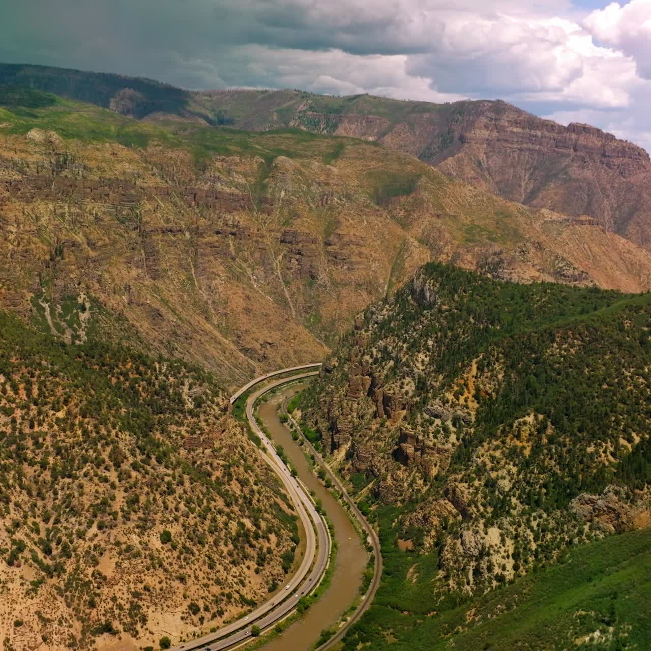 Gorgeous view of beautiful mountains of Colorado State, USA. Wavy river separating the mountains and roads going along the waterfront from top view